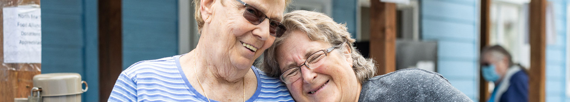 two women smiling and leaning on each other
