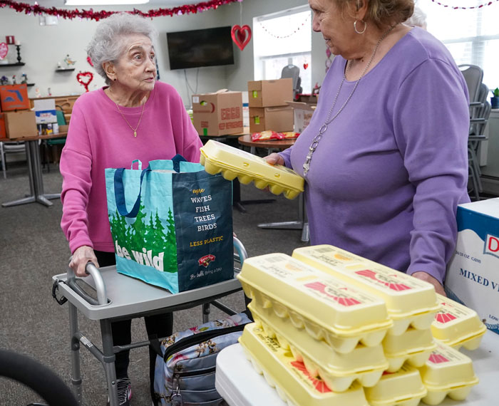 Woman placing eggs to a shopping bag of another woman